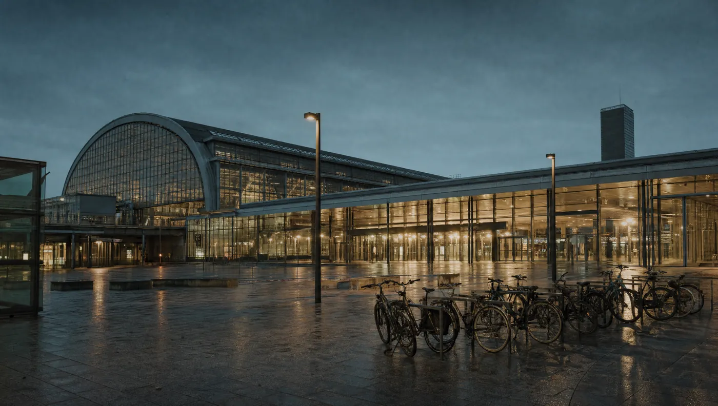 Der Hauptbahnhof Münster zur blauen Stunde mit Fahrradstellplätzen davor.