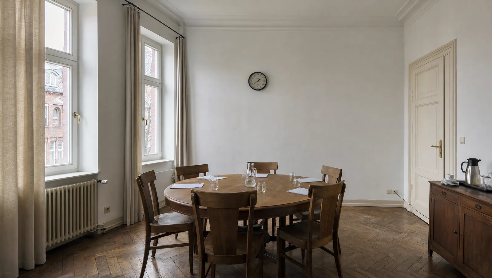 Runder Tisch mit sechs Stühlen in einem holzvertäfelten Raum.